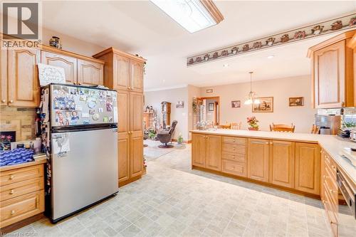 Spacious kitchen featuring extensive wood-finish cabinetry, a large kitchen island with counter seating, neutral-toned flooring, and recessed lighting - 875 Safari Road, Hamilton, ON 