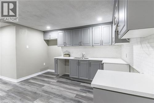 Gray shaker-style cabinetry, white countertops, subway tile backsplash, stainless steel sink, and wood-finish flooring - 15 Spiers Crescent, Cambridge, ON - Indoor Photo Showing Kitchen