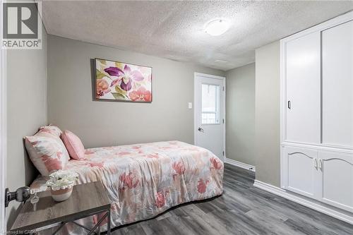 Wood-finish flooring, built-in white cabinetry with decorative trim, white paneled door with glass insert, and flush-mount ceiling light - 15 Spiers Crescent, Cambridge, ON - Indoor Photo Showing Bedroom