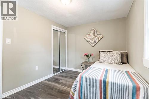 Wood-finish flooring, mirrored sliding closet doors, and a window with white trim - 15 Spiers Crescent, Cambridge, ON - Indoor Photo Showing Bedroom