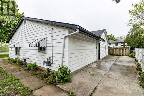 White siding exterior with black and white striped awnings and a concrete driveway - 15 Spiers Crescent, Cambridge, ON - Outdoor With Exterior