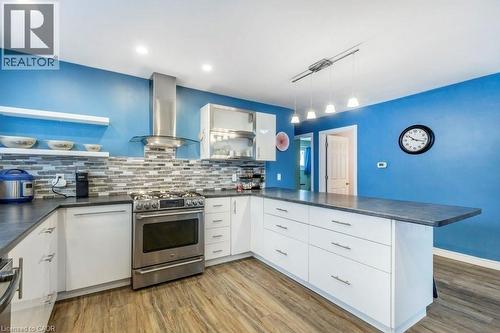 Kitchen featuring wood-finish flooring, white cabinetry with silver hardware, an integrated stainless steel range, and a tiled backsplash - 510 Oakridge Place, Waterloo, ON - Indoor Photo Showing Kitchen With Upgraded Kitchen