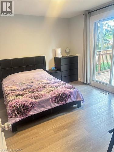 Wood-finish flooring, sliding glass door, private deck, and a contemporary dark wood-finish dresser - 510 Oakridge Place, Waterloo, ON - Indoor Photo Showing Bedroom