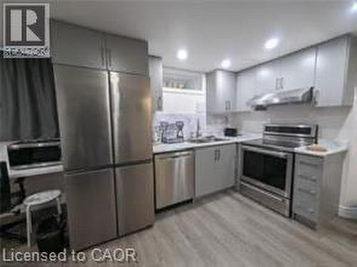 Stainless steel appliances, recessed ceiling lighting, light-toned cabinetry, wood-finish flooring, and a subway tile backsplash - 510 Oakridge Place, Waterloo, ON - Indoor Photo Showing Kitchen With Stainless Steel Kitchen