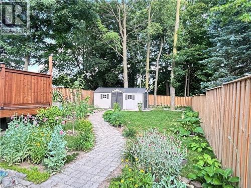 Expansive backyard featuring a stone paver pathway, manicured lawn, established garden beds, and a wood privacy fence - 510 Oakridge Place, Waterloo, ON - Outdoor