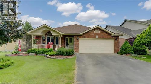 Brick facade residential property featuring a covered front porch with white railings, an attached two-car garage with a light-colored door, a paved driveway, and a front lawn with established landsca - 599 Coldstream Drive, Waterloo, ON - Outdoor With Deck Patio Veranda With Facade