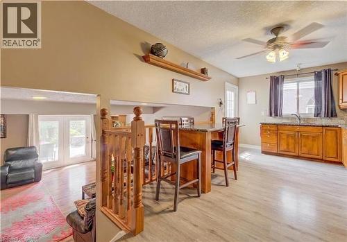 Open-concept living space featuring wood-finish flooring, a kitchen island with seating, wood cabinetry, a ceiling fan, and French doors leading to exterior - 599 Coldstream Drive, Waterloo, ON - Indoor Photo Showing Dining Room