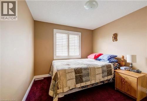 Bedroom featuring a single window with white plantation shutters, neutral tone walls, and deep red carpeting - 599 Coldstream Drive, Waterloo, ON - Indoor Photo Showing Bedroom