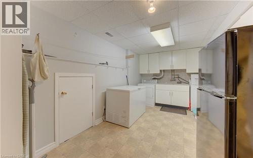 Utility room featuring light-toned square floor tiles, white wall cabinetry, a utility sink, and a drop ceiling - 599 Coldstream Drive, Waterloo, ON - Indoor Photo Showing Laundry Room