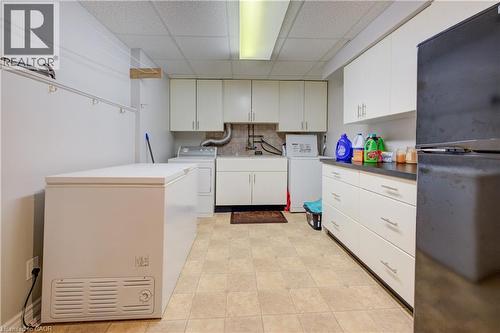 Utility room featuring ample cabinetry, a drop-in sink, and a tiled backsplash - 599 Coldstream Drive, Waterloo, ON - Indoor Photo Showing Laundry Room