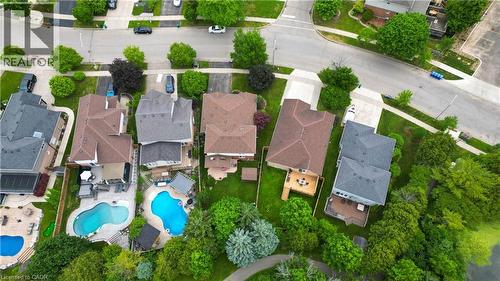 Aerial perspective showcasing a residential neighborhood with properties featuring varied rooflines, private swimming pools, and extensive green space - 599 Coldstream Drive, Waterloo, ON - Outdoor With In Ground Pool With View