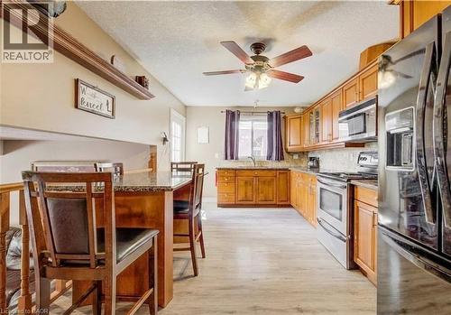 Kitchen featuring wood-finish cabinetry, stainless steel appliances, granite-style countertops, and a tile backsplash - 599 Coldstream Drive, Waterloo, ON - Indoor Photo Showing Kitchen