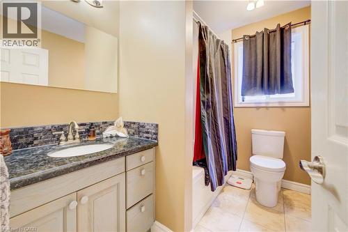 Bathroom featuring a vanity with a dark stone countertop, an oval undermount sink, and a tiled backsplash - 599 Coldstream Drive, Waterloo, ON - Indoor Photo Showing Bathroom