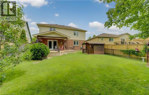 Expansive green lawn with a wooden deck featuring a covered patio, double glass doors, and a wood-sided shed - 599 Coldstream Drive, Waterloo, ON - Outdoor