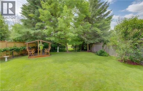 Expansive backyard featuring a manicured lawn, established trees, and a wooden gazebo structure - 599 Coldstream Drive, Waterloo, ON - Outdoor With Backyard