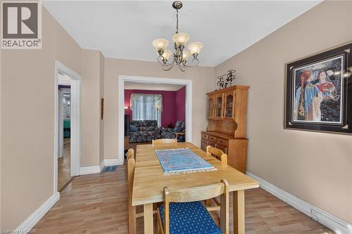 Dining area with wood-finish flooring, a decorative chandelier, and neutral wall tones - 230 Picton Street E, Hamilton, ON - Indoor Photo Showing Dining Room