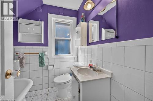 Bathroom featuring white wall tiling, vanity with integrated sink, wall-mounted mirror, and a window - 230 Picton Street E, Hamilton, ON - Indoor Photo Showing Bathroom