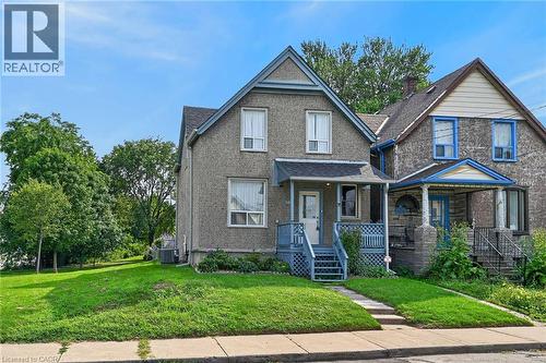 Two-story residence with a covered front porch featuring a lattice railing, a peaked gable roof, and a paved walkway leading to the entrance - 230 Picton Street E, Hamilton, ON - Outdoor With Facade