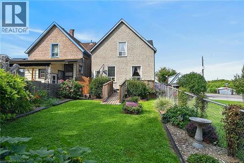 Manicured lawn with established garden beds, bordered by a chain-link fence - 230 Picton Street E, Hamilton, ON - Outdoor With Deck Patio Veranda