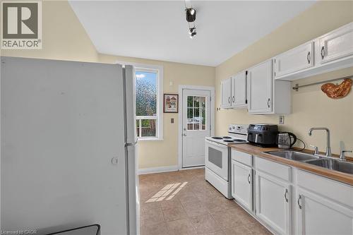 Galley-style kitchen featuring white cabinetry, wood-finish countertops, and a double basin stainless steel sink - 230 Picton Street E, Hamilton, ON - Indoor Photo Showing Kitchen With Double Sink