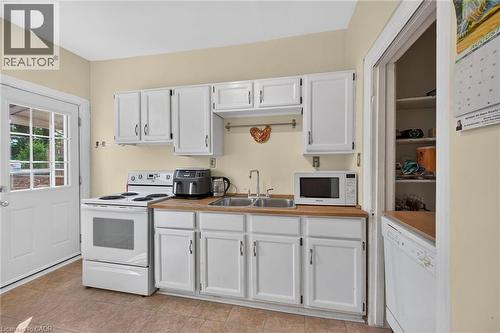 White cabinetry with wood-finish countertops, stainless steel double basin sink, and tile flooring - 230 Picton Street E, Hamilton, ON - Indoor Photo Showing Kitchen With Double Sink