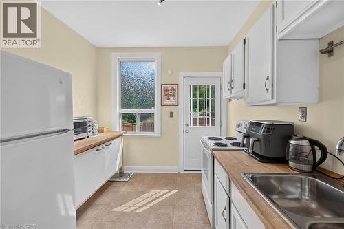 Kitchen featuring tile flooring, wood-finish countertops, white cabinetry, and white appliances - 230 Picton Street E, Hamilton, ON - Indoor Photo Showing Kitchen