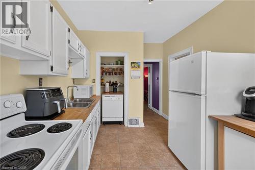 Kitchen featuring white cabinetry, wood-finish countertops, stainless steel sink, and tile flooring - 230 Picton Street E, Hamilton, ON - Indoor Photo Showing Kitchen With Double Sink