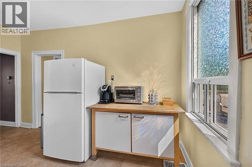 White two-door refrigerator, wood-finish countertop, white base cabinetry with brushed nickel hardware, and a window with textured glass - 230 Picton Street E, Hamilton, ON - Indoor