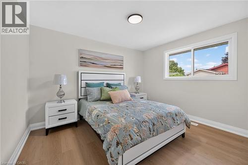 Wood-finish flooring with white baseboards, light neutral wall paint, and a white framed window - 40 Purdy Crescent, Hamilton, ON - Indoor Photo Showing Bedroom