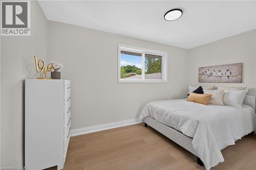 Neutral wall tones, wood-finish flooring, white trim, and a flush-mount ceiling light - 40 Purdy Crescent, Hamilton, ON - Indoor Photo Showing Bedroom