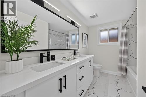 Dual vanity with integrated sinks and matte black fixtures, set against a large framed mirror with linear lighting - 40 Purdy Crescent, Hamilton, ON - Indoor Photo Showing Bathroom