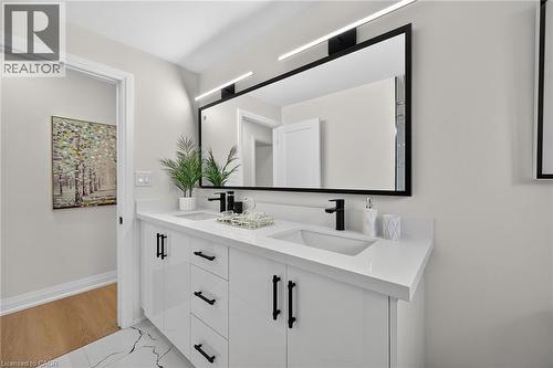 Dual vanity with integrated rectangular sinks, white countertops, black-framed mirror, and black wall-mounted lighting - 40 Purdy Crescent, Hamilton, ON - Indoor Photo Showing Bathroom