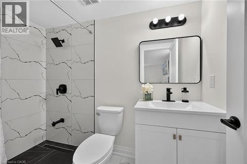 Modern bathroom featuring a single vanity with storage, a rectangular mirror, and a wall-mounted light fixture - 40 Purdy Crescent, Hamilton, ON - Indoor Photo Showing Bathroom