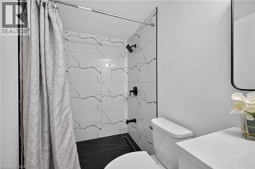 Shower with white and black patterned tiling, black floor tiling, and matte black fixtures - 40 Purdy Crescent, Hamilton, ON - Indoor Photo Showing Bathroom