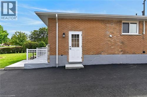 Brick exterior with white door, aluminum railing, exterior lighting fixture, and paved surface - 40 Purdy Crescent, Hamilton, ON - Outdoor