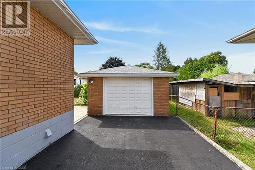Detached brick garage with a panel-style door, asphalt driveway, and a chain-link property line - 40 Purdy Crescent, Hamilton, ON - Outdoor With Exterior