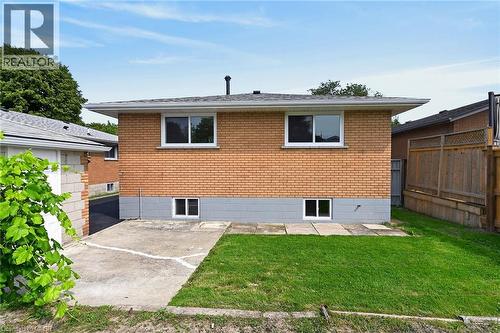 Brick exterior with white window frames, a concrete patio, and a grassy area - 40 Purdy Crescent, Hamilton, ON - Outdoor With Exterior