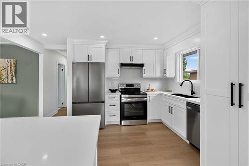 White cabinetry with black hardware, stainless steel appliances, wood-finish flooring, white countertops, and recessed lighting - 40 Purdy Crescent, Hamilton, ON - Indoor Photo Showing Kitchen With Double Sink
