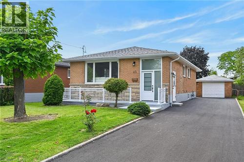Brick exterior with stone accents, white entry door with frosted glass panels, detached single-car garage, and an asphalt driveway - 40 Purdy Crescent, Hamilton, ON - Outdoor