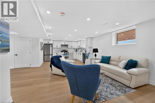 Open-concept living area featuring wood-finish flooring, recessed lighting, a modern kitchen with white cabinetry, stainless steel appliances, and a compact window - 40 Purdy Crescent, Hamilton, ON - Indoor Photo Showing Living Room