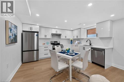 White cabinetry with dark hardware, stainless steel appliances, wood-finish flooring, recessed lighting, and a black gooseneck faucet - 40 Purdy Crescent, Hamilton, ON - Indoor Photo Showing Kitchen