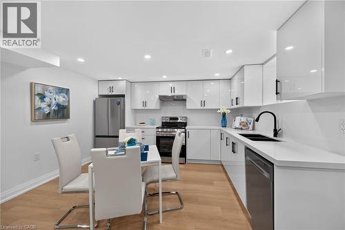 Modern kitchen featuring stainless steel appliances, white flat-panel cabinetry, light wood-finish flooring, recessed lighting, and a black single-basin sink with a matte black faucet - 40 Purdy Crescent, Hamilton, ON - Indoor Photo Showing Other Room