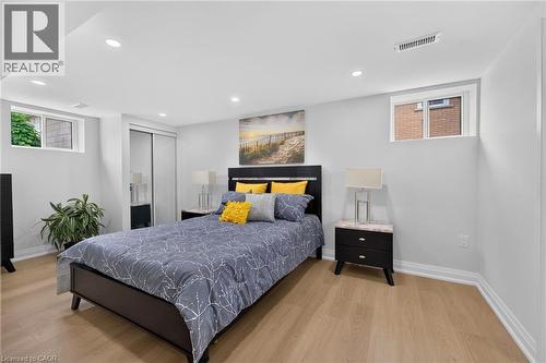 Recessed lighting, wood-finish flooring, white trim, two windows, and a sliding door closet with mirrored panels - 40 Purdy Crescent, Hamilton, ON - Indoor Photo Showing Bedroom