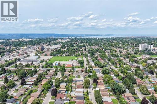 Expansive aerial perspective showcasing a residential neighborhood with detached homes, mature trees, and a distant water body - 40 Purdy Crescent, Hamilton, ON - Outdoor With View