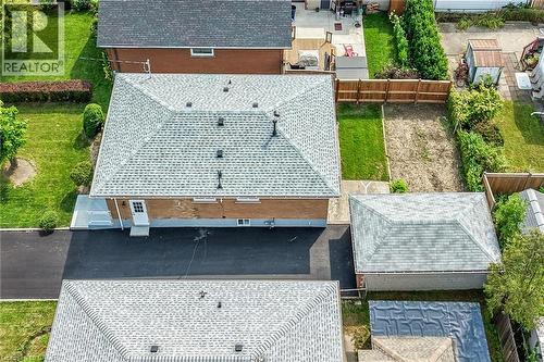 Expansive paved driveway leading to the property, pitched roof with asphalt shingles, mature trees and shrubs, brick exterior, and a wooden fence defining the property line - 40 Purdy Crescent, Hamilton, ON - Outdoor With Deck Patio Veranda
