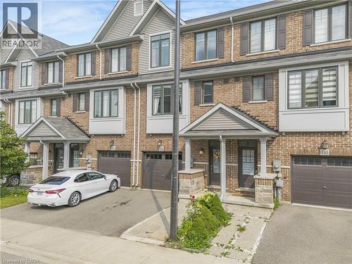 Brick exterior with gabled roofline, multiple windows with dark shutters, covered entry, and attached garage - 1890 Rymal Road E Unit# 144, Hamilton, ON - Outdoor With Facade