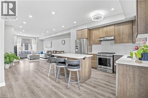 Open-concept living space featuring wood-finish flooring, recessed lighting, and a kitchen island with seating - 1890 Rymal Road E Unit# 144, Hamilton, ON - Indoor Photo Showing Kitchen With Stainless Steel Kitchen With Upgraded Kitchen
