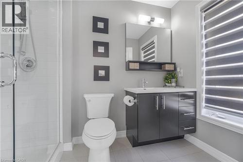 Modern bathroom featuring a glass-enclosed shower, dark wood-finish vanity with chrome pulls, integrated sink, and large wall-mounted mirror - 1890 Rymal Road E Unit# 144, Hamilton, ON - Indoor Photo Showing Bathroom