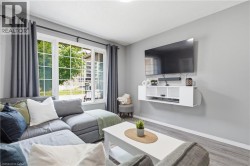 White-framed windows with grid patterns, light gray walls, wood-finish flooring, and a floating media console - 