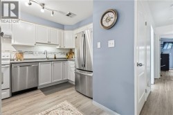 Kitchen featuring white cabinetry, stainless steel appliances, a tile backsplash, track lighting, and wood-finish flooring - 